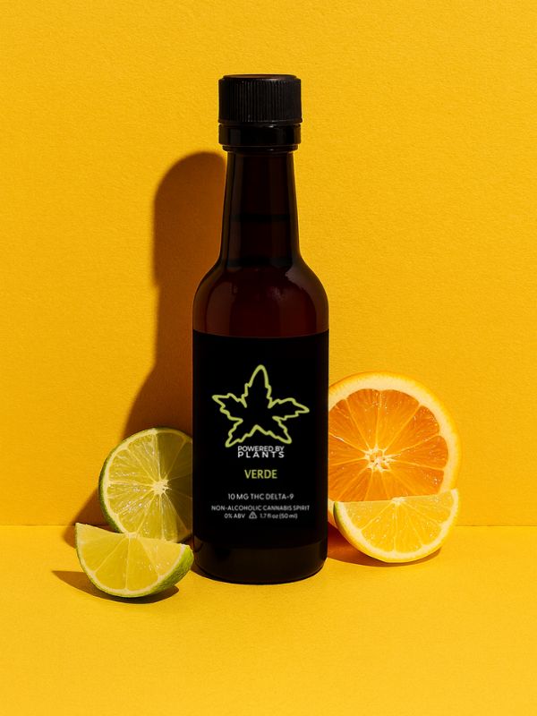 Bottle of 'Verde' on a yellow background with citrus fruits